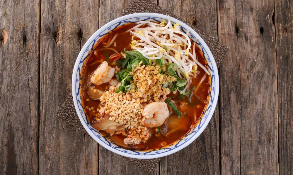 Spicy shrimp noodle soup with bean sprouts, peanuts, and herbs in red broth at Canto House, a Chinese restaurant in Philadelphia